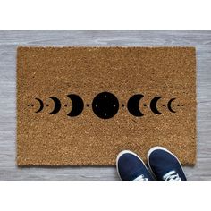 a door mat with the moon phases on it and two feet standing in front of it