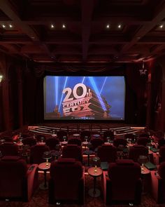 an empty theater with red chairs and a large screen on the wall that says 20th