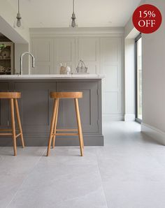 two wooden stools sit in front of an island with marble countertops and white walls