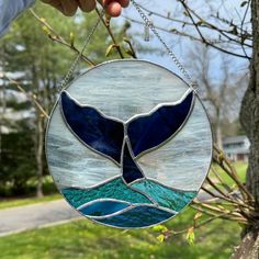 a stained glass whale tail hanging from a tree