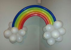 a rainbow shaped balloon hangs from the ceiling in front of a mirror with balloons attached to it