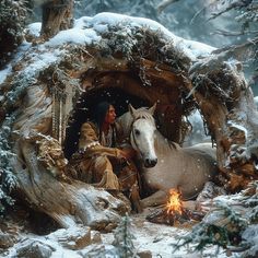 a native american man sitting next to a white horse in the snow near a fire pit