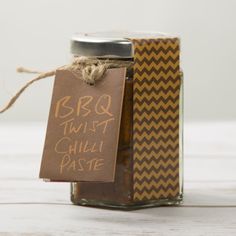 a jar filled with chili paste sitting on top of a white wooden table next to a tag