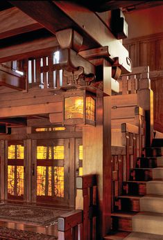 the inside of a wooden house with stained glass windows and wood staircase leading up to it