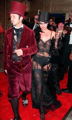 a man and woman dressed in costume walking on a red carpet