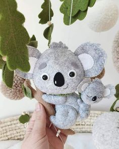 a stuffed koala bear hanging from a tree with two smaller koala bears attached to it