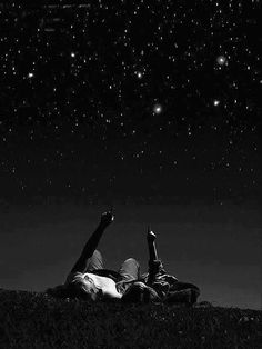 two people laying in the grass under stars