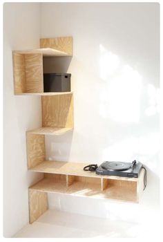 a record player sitting on top of a wooden shelf next to a wall mounted speaker