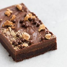 a piece of cake with chocolate frosting and crumbs on the top, sitting on a white surface