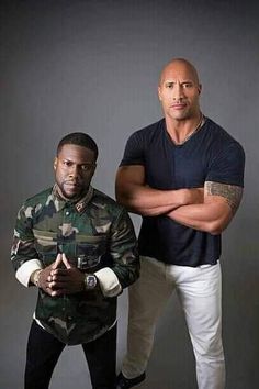 two men standing next to each other in front of a gray background with their arms crossed