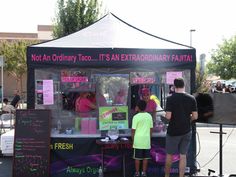 two people standing in front of a food stand with writing on the side of it that says, not an ordinary taco it's extra ordinary futta