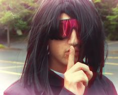 a man with long black hair and red sunglasses is making a finger to his lips