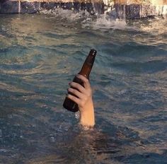 a person holding a beer bottle in the water