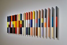 an art piece is hanging on the wall in front of a row of different colored sticks