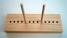 a wooden peg board with four holes in the middle and two sticks sticking out of it