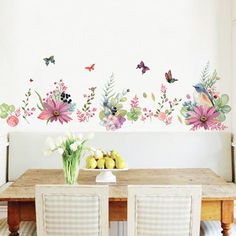 a dining room table with two chairs and flowers on the wall