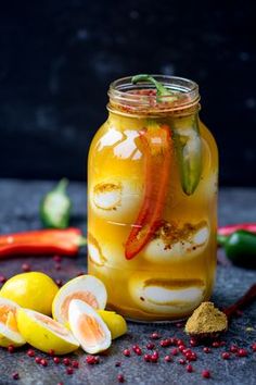 a jar filled with liquid next to sliced fruit and spices