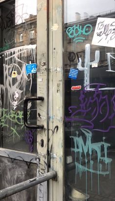 graffiti on the side of a building in front of a door with bars and windows