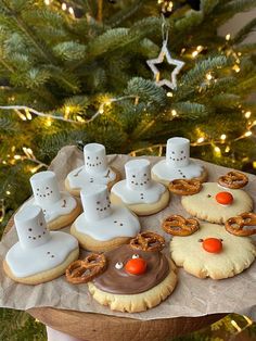 a person holding a tray with cookies and pretzels in front of a christmas tree