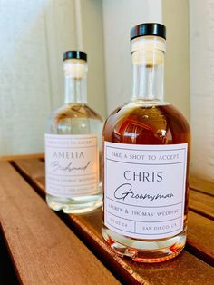 two bottles of alcohol sitting on top of a wooden table