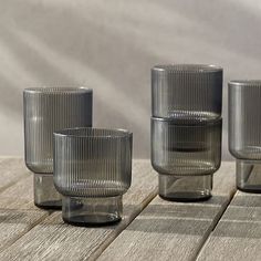 four glass cups sitting on top of a wooden table next to each other with a slice of lemon in the middle