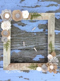 a wooden frame decorated with flowers and other items on a blue painted wood background that is made from scrapbook pages