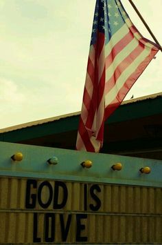 an american flag flying from the top of a building with god is love written on it