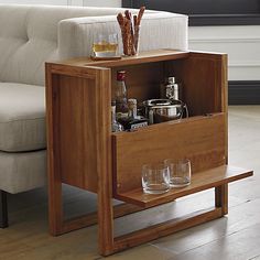 a wooden table with two glasses on it and an open drawer in the middle that holds drinks