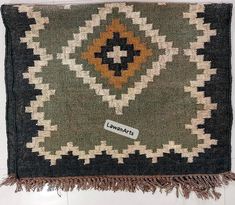 a green and yellow rug with fringes on the bottom is laying on a white surface