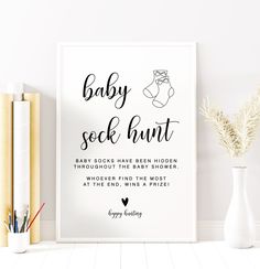 a baby sock hunt poster on the wall next to books and vase with flowers in it