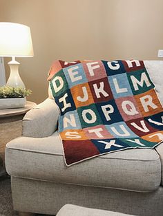 a couch with a blanket on it and a lamp in the corner next to it