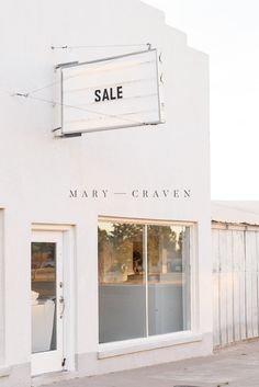 a white building with a sale sign on it's front window and the words mary - craven written in black