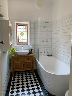 a black and white checkered floor in a bathroom with a bathtub, sink and mirror