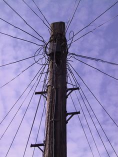 an electric pole with many wires attached to it and the sky in the back ground