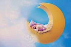 a baby is sleeping on the moon with clouds in the sky behind it and blue skies above