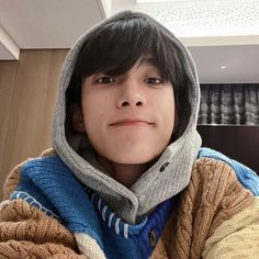 a boy wearing a hoodie taking a selfie