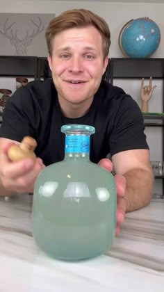 a man sitting at a table with a green bottle in front of him and a corkscrew