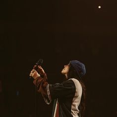 a man with long hair holding a microphone and wearing a beanie on top of his head