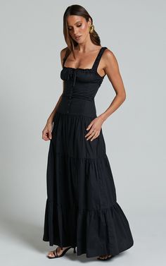 a woman in a black dress posing for the camera with her hands on her hips