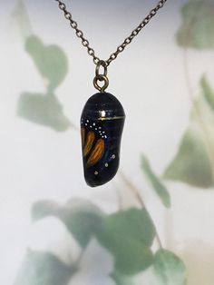 "The chrysalis - a symbol of transformation or metamorphosis. Gorgeous monarch butterfly chrysalis pendant, sculpted from clay and hand painted by me. This style is more contemporary than my realistic ones, more of an \"arty\" feel. No two are exactly the same. Comes with a 45cm (18 inch) chain in either gold tone, silver, antique bronze or black leather cord for a more bohemian feel. Please specify your choice when ordering :) Makes a beautiful gift for a girlfriend, wife or mother! Check my ot Unique Handmade Butterfly Necklace, Handmade Unique Butterfly Shaped Necklace, Handmade Unique Butterfly Necklace, Unique Hand Painted Butterfly Jewelry, Hand Painted Butterfly Jewelry Gift, Hand Painted Butterfly Jewelry For Gift, Monarch Chrysalis, Butterfly Chrysalis, Portfolio Ideas