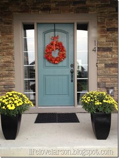 a blue front door with yellow flowers and a wreath