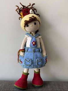 a crocheted doll is standing against a wall with her hair in a bun