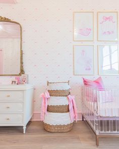 a baby's room with pink and white wallpaper, crib, dresser and mirror