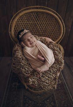 a newborn baby is wrapped in a blanket on a wicker chair