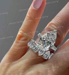 a woman's hand with a diamond ring on top of her finger and an oval shaped