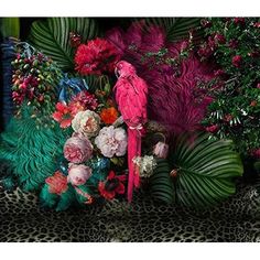 a parrot sitting on top of a lush green plant next to flowers and plants in front of a leopard print wall