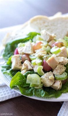 a salad with chicken, lettuce and cucumbers on a white plate