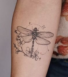 a woman's arm with a dragonfly tattoo on it