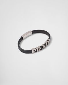 Push-lock clasp Metal lettering logo Leather Bracelet With Palladium Hardware As Gift, Luxury Silver Jewelry With Engraved Logo, Classic Formal Jewelry With Engraved Logo, Classic Black Jewelry With Logo Charm, Modern Black Bracelets With Palladium Hardware, Designer Silver Leather Bracelet With Palladium Hardware, Luxury Black Leather Jewelry, Luxury Black Leather Bracelet With Palladium Hardware, Black Leather Bracelet With Palladium Hardware For Formal