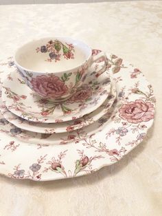 a stack of four plates sitting on top of a table covered in floral print cloth